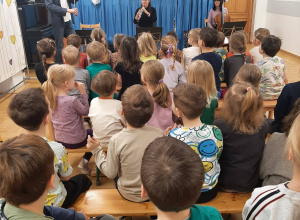Dzieci siedzące na ławkach podczas koncertu.