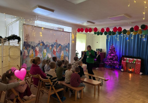 Dyrektor przemawia, dzieci i goście siedzą na sali gimnastycznej.