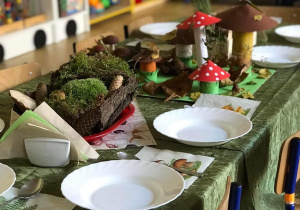 Stół nakryty na zielono z elementami grzybów.