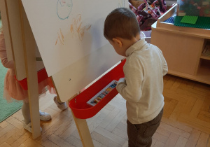 Dzieci malujące na sztaludze.