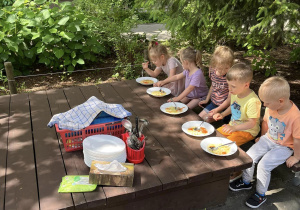 Dzieci jedzące obiad w ogrodzie.