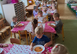 Dzieci jedzące obiad, obrusy w kropki.