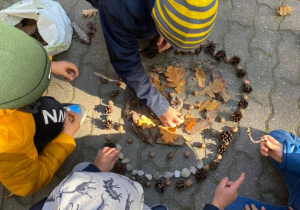 Dzieci wykonują mandale z materiałów znalezionych w ogrodzie.