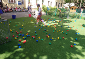 Zabawa dzieci z kolorowymi piłkami na dworze.